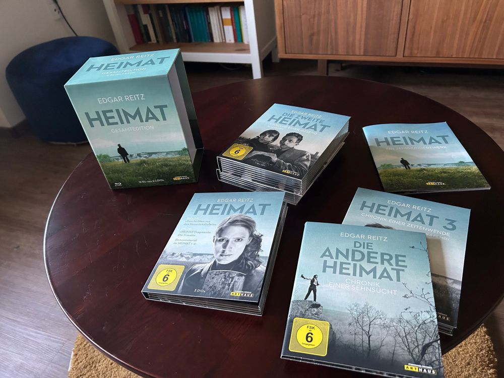 Edgar Reitz - Heimat Gesamtedition auf 16 Blu-Rays und 3 DVDs in verschiedenen Schubern aufgeteilt mit Booklet auf rundem Holztisch
