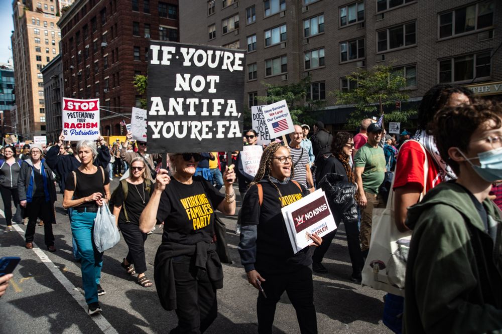 Woman in the #NoKings march holding a sign reading, "If you're not antifa, you're fa."