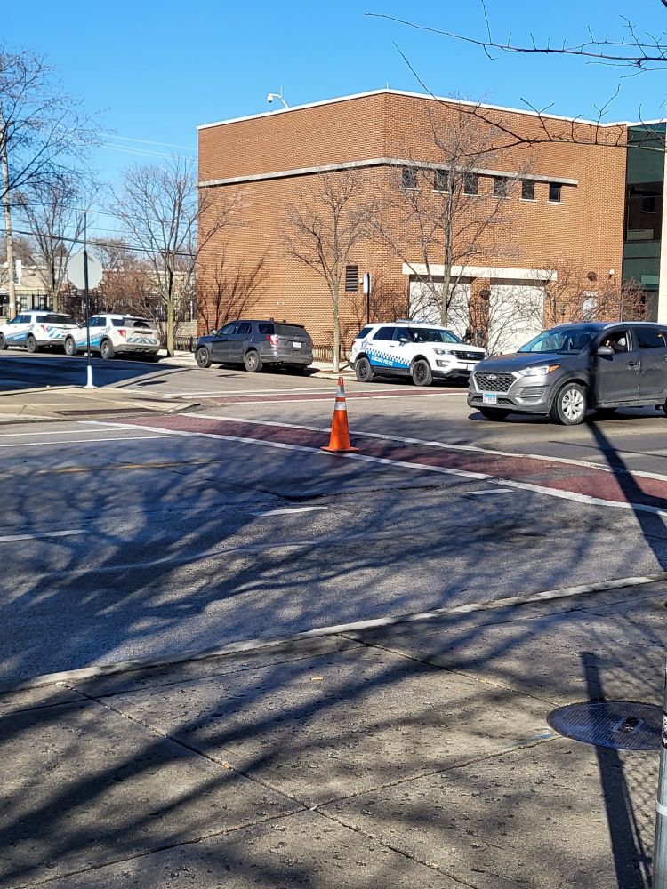An orange traffic cone in the middle of a crosswalk. Placed as a diy traffic calming measure. 