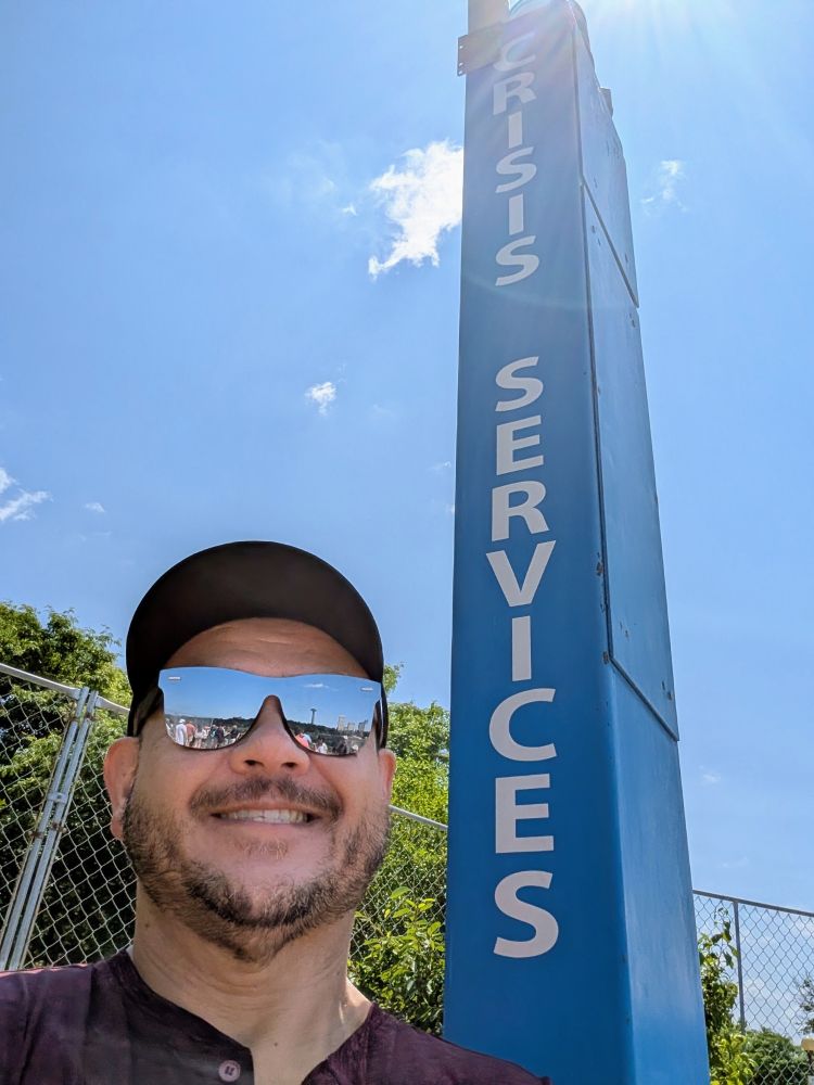 Man smiling next to Crisis Services phone pillar