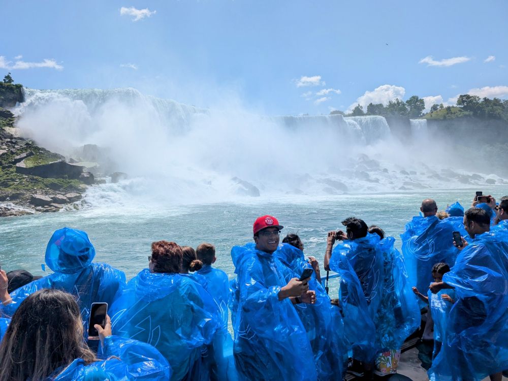 People in blue plastic ponchos on the deck of a boat near Niagara Falls