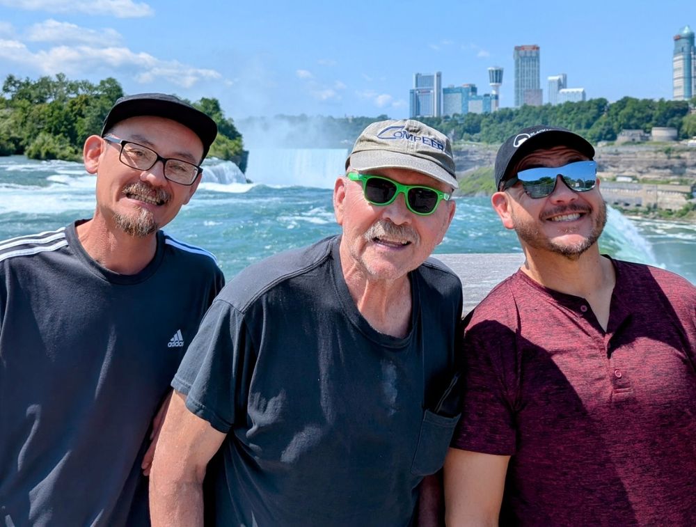 Three men smiling at Niagara Falls