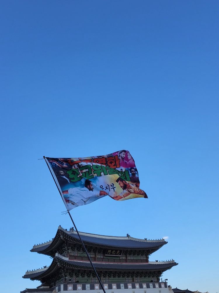 푸른 하늘 아래 경복궁 광화문 앞에서 펄럭이는 인도영화 포교위원회 서울지부 깃발.