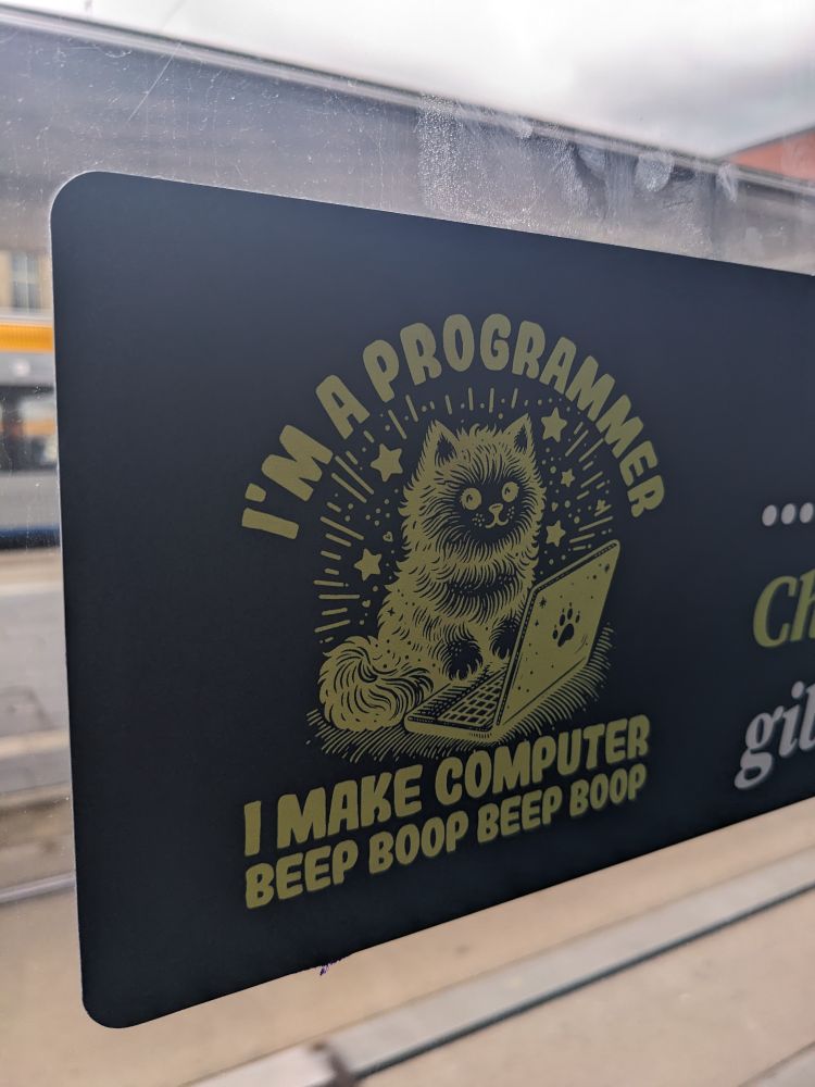 Sticker on window of public transport which shows a cat in front of a laptop. The text reads "I'm a programmer. I make Computer Beep Boop Beep Boop"