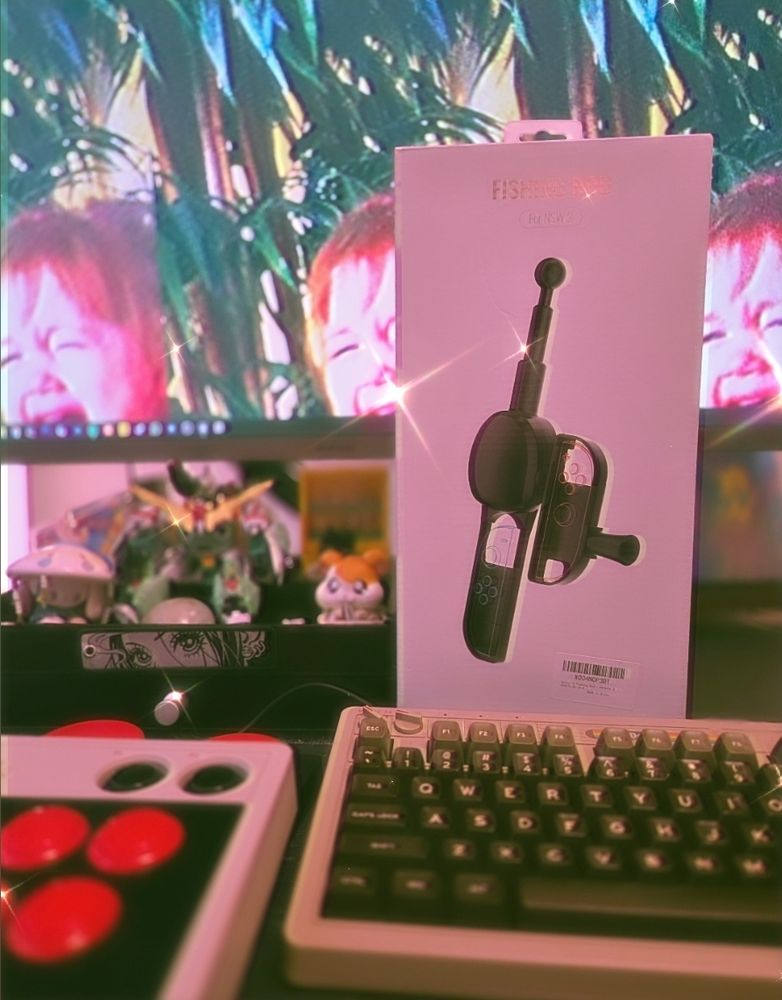 Silly Instagram filtered photo of my desk, showcasing a fishing rod Switch 2 controller adapter, a fight stick, and my keyboard in front of my monitor