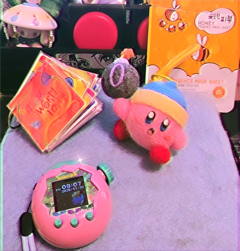 (Mostly) completed needle felted bomb Kirby next to our daily affirmation (I am worth loving) and our tamagotchi! Behind it is the packaging from the facemask I wore today (it was honey essence)