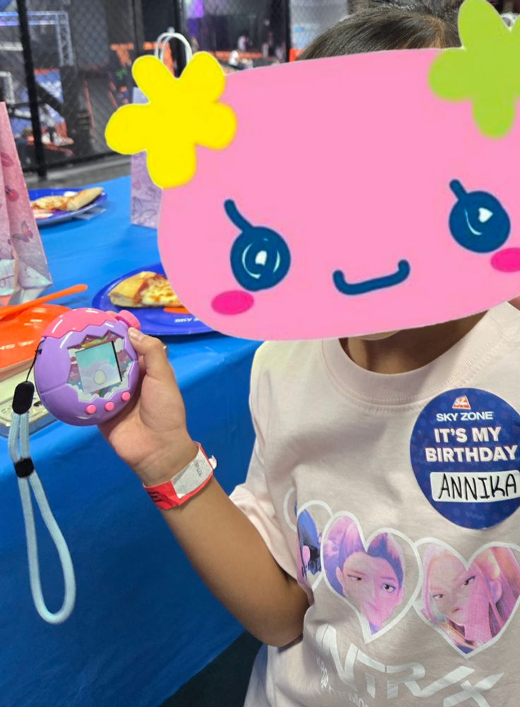 Edited photo of my sister and her tamagotchi covering her face with a Tama character 