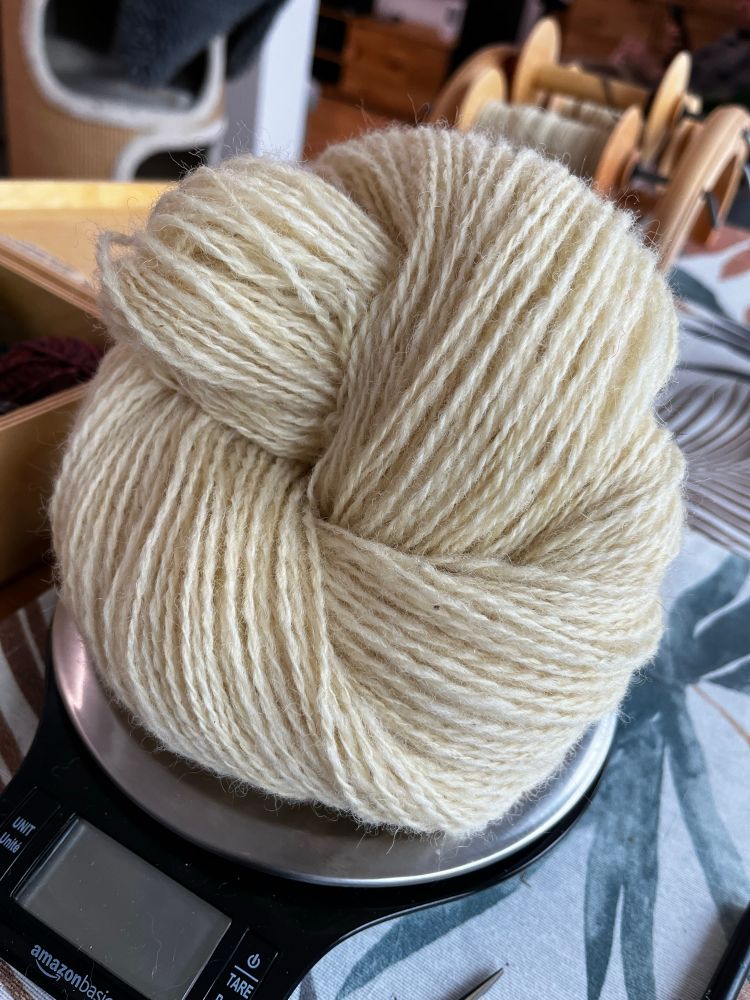 Handspun natural coloured white yarn on a scale. 