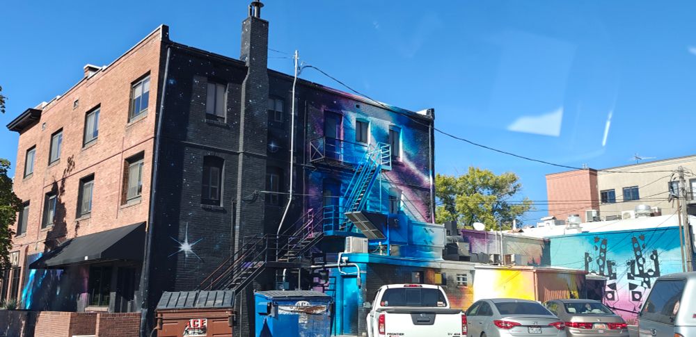 A building with blue and purple space clouds painted. Along with some futuristic cactus plants painted on the wall 