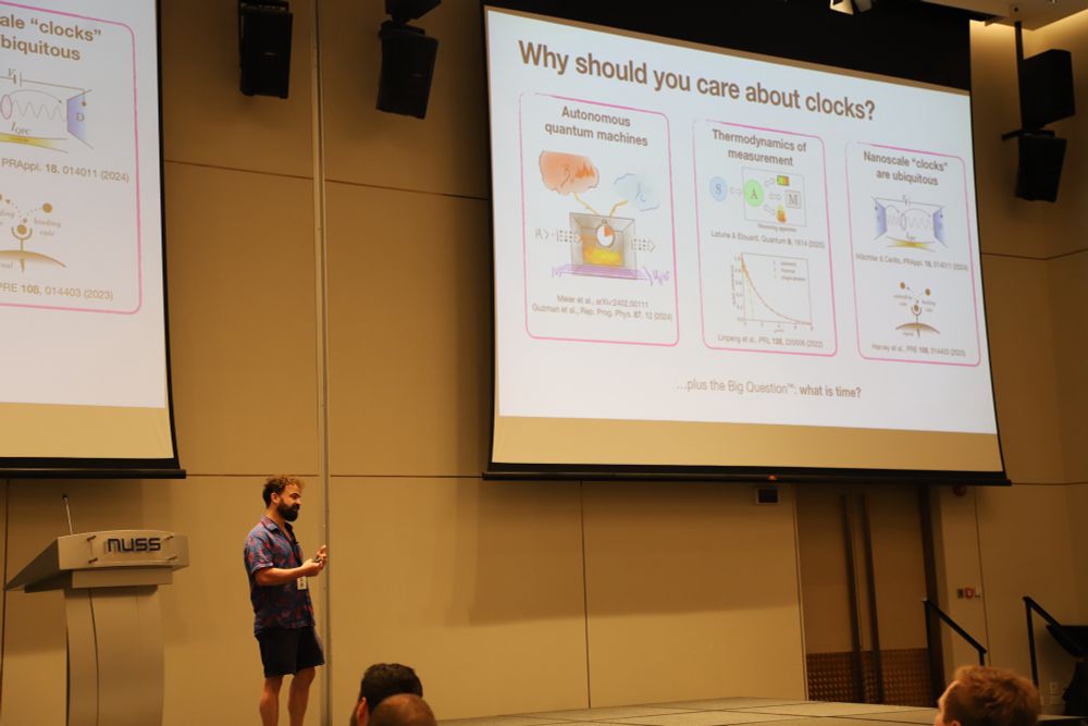 Mark on stage giving a talk at QTD 2025. The slide motivates why the audience of quantum thermodynamics researchers should be interested in clocks. 