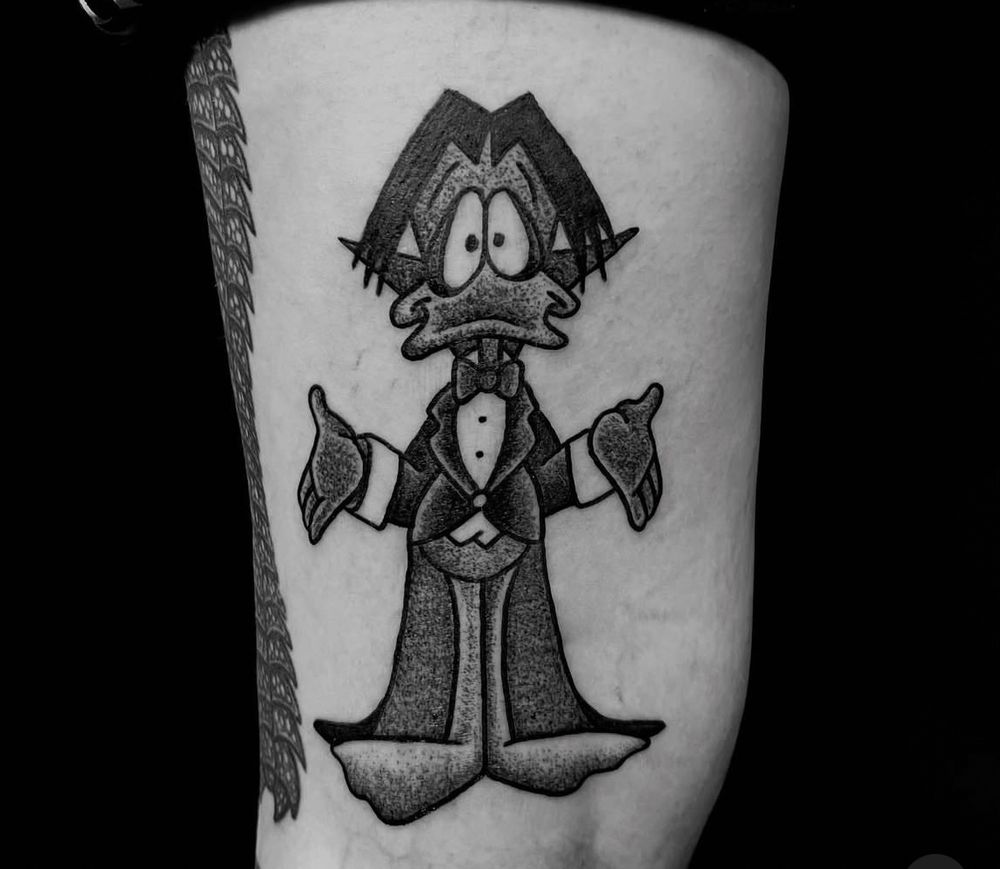 Photo of the back of Katie’s leg showing a tattoo of count duckula in black and grey. By @kingofbones (instagram) at Momento Mori, Glasgow. 