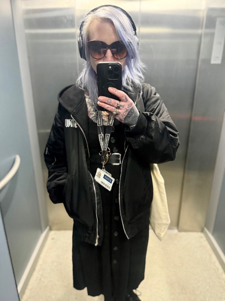 Mirror selfie of Katie dressed in black with headphones and sunglasses on