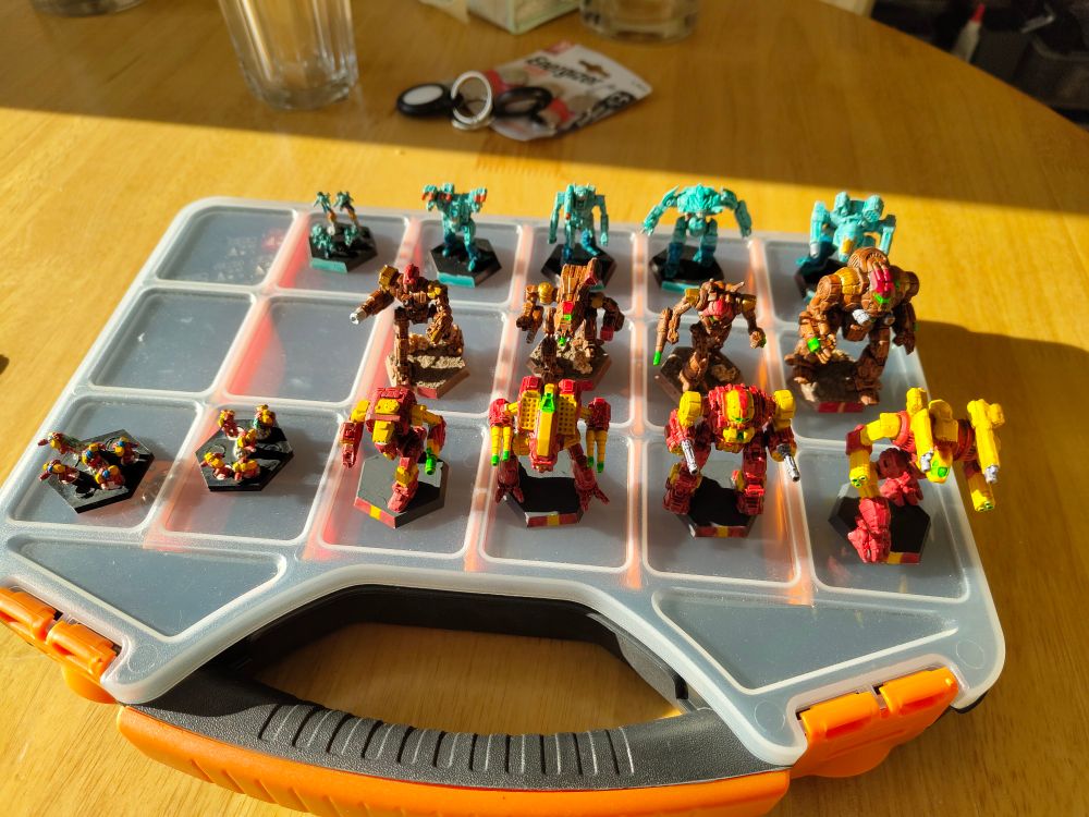 12 Battlemechs on a carry case, 4 in Clan Hell's Horses Gamma Galaxy Colours, 4 in Taurian Concordat Guard colours and 4 in Clan Sea Fox Spina Khanate colours, along with 2 bases of Hells Horse Battle Armour and 1 base of Sea Fox Battle Armour 