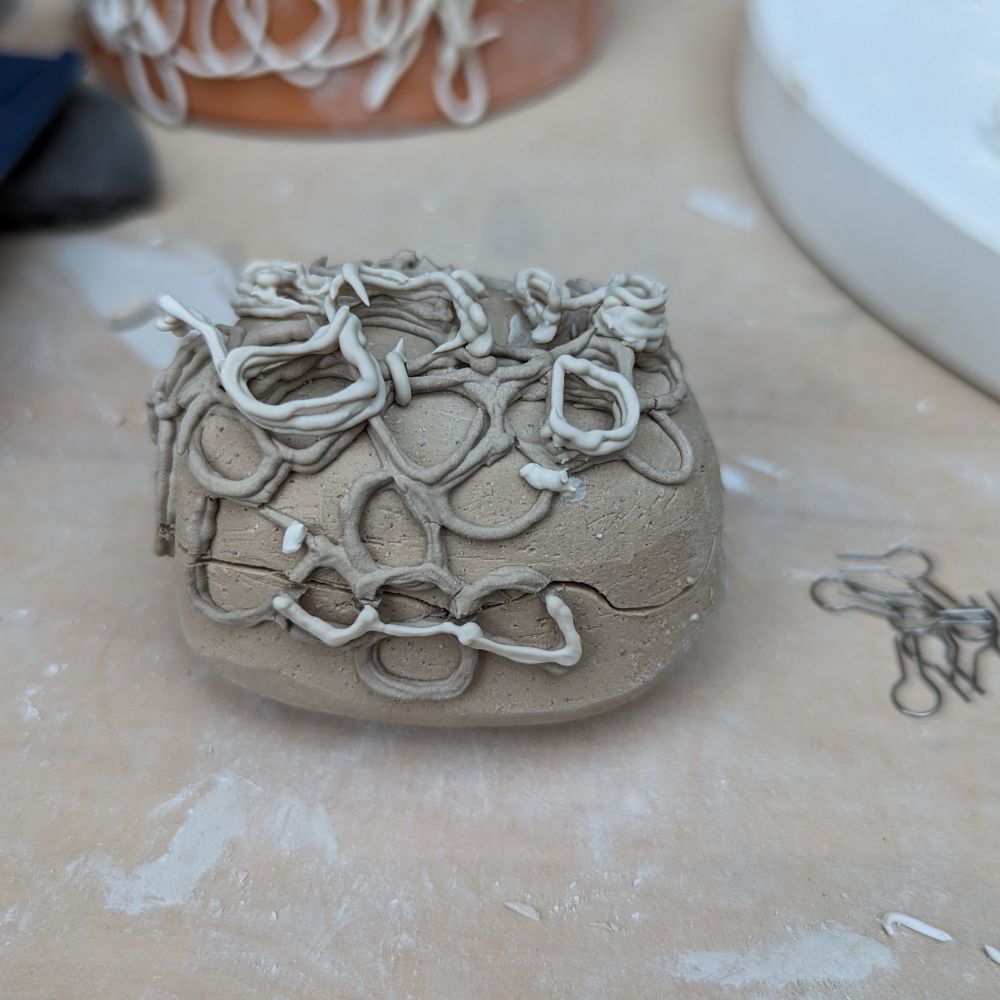 Handmade ceramic box decorated with slip-trailed squiggles. Greenware.