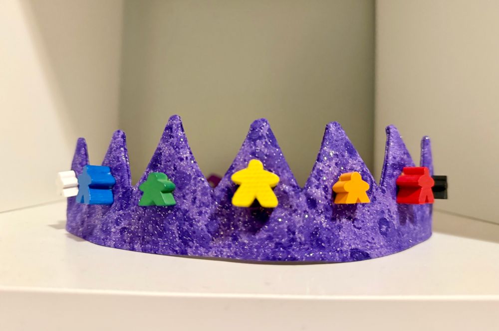 fabric crown adorned with game pieces 