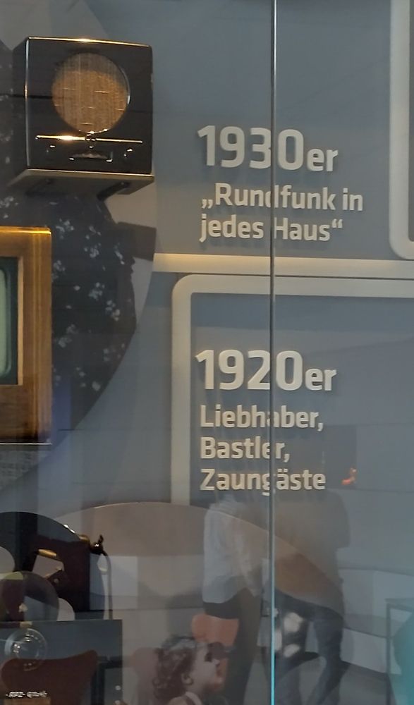Image shows a detail from the exhibition on radio broadcasting, one line reading in German: 1920s - tinkerer, peanut gallery/ 1930s - radio in every house