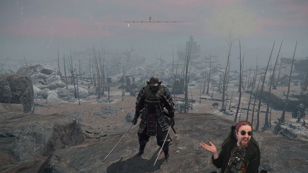 Will, a smiling streamer with purple hair and dark glasses, is smiling and gesturing at a character overlooking a dreary portion of the Caelid landscape in Elden Ring.