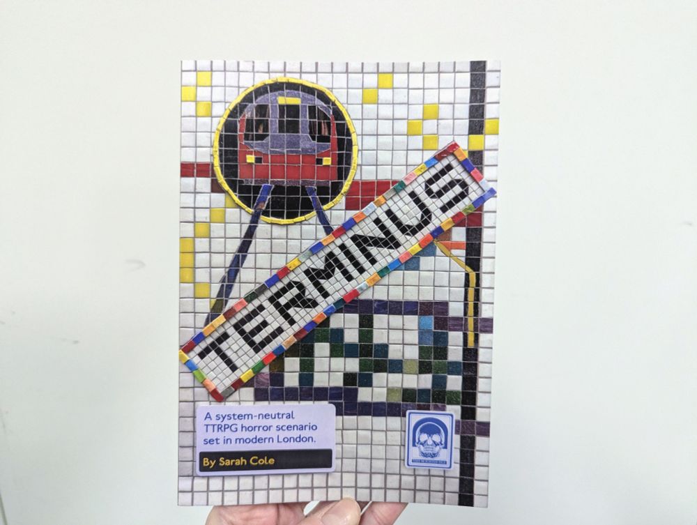 A less glamorous photo of TERMINUS, held aloft against a scuffed white wall. The cover is a photograph of a mosaic and affixed signage. The mosaic spells out the word 'TERMINUS' and includes a design of an incoming Tube train. 