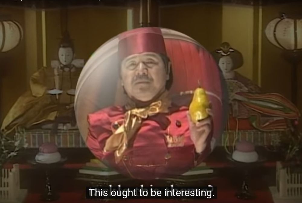 Screenshot from Episode 1, Season 2 of Iron Chef where Iron Chef France appears within an orb, with a traditional Japanese art set piece as the background. 