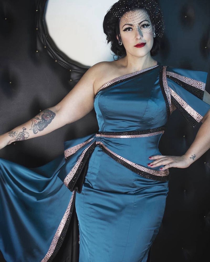 Woman (Kitty Kin Evil) posing in deep teal coloured cocktail gown.