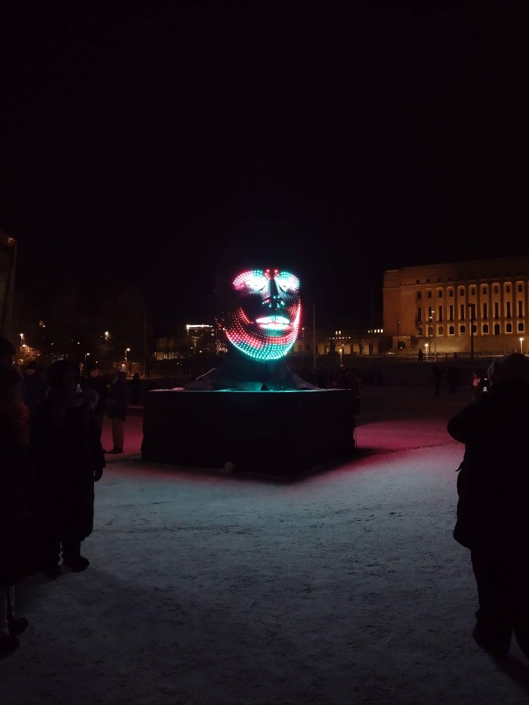An illuminated sculpture of a human head with lead lights lighting it up in different patterns.
