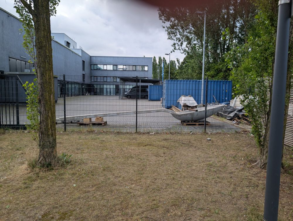 Abgesperrter Bereich hinter der Mensa, paar Container, Auto - vorne ein 5 Meter langer Löffel 