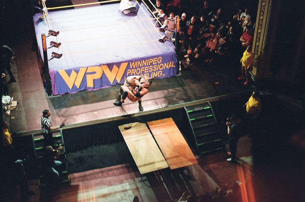 A wrestler chokeslams another wrestler though a table