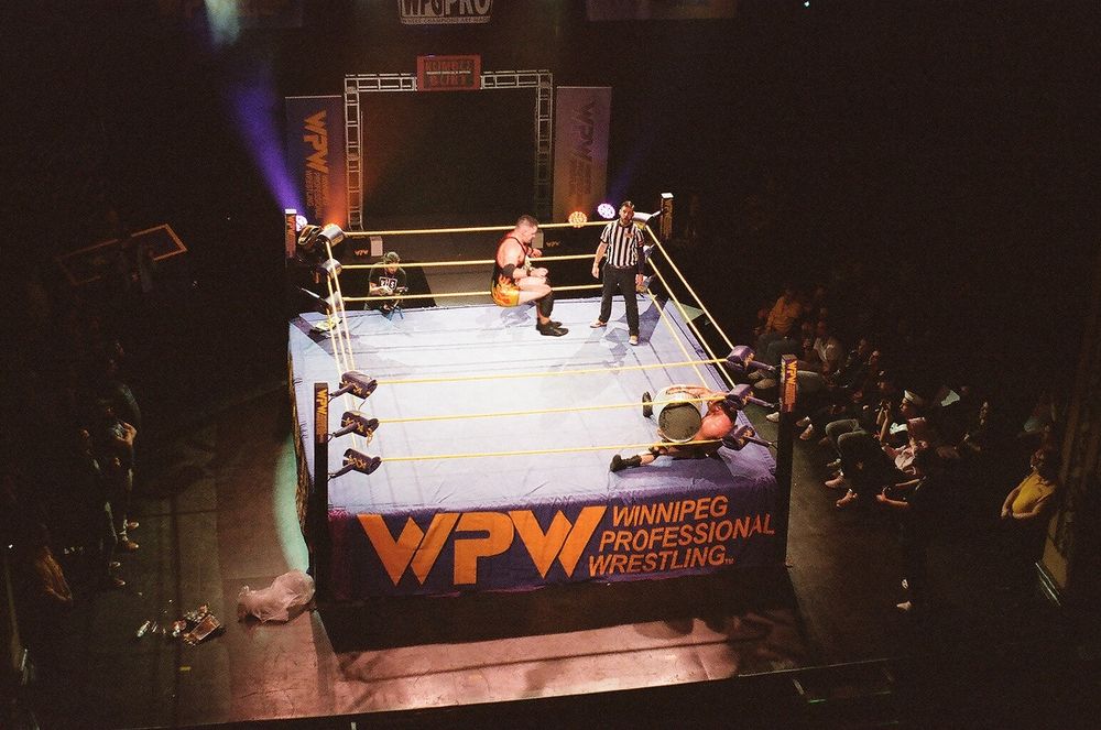 A wrestler soars across the ring to drop kick another