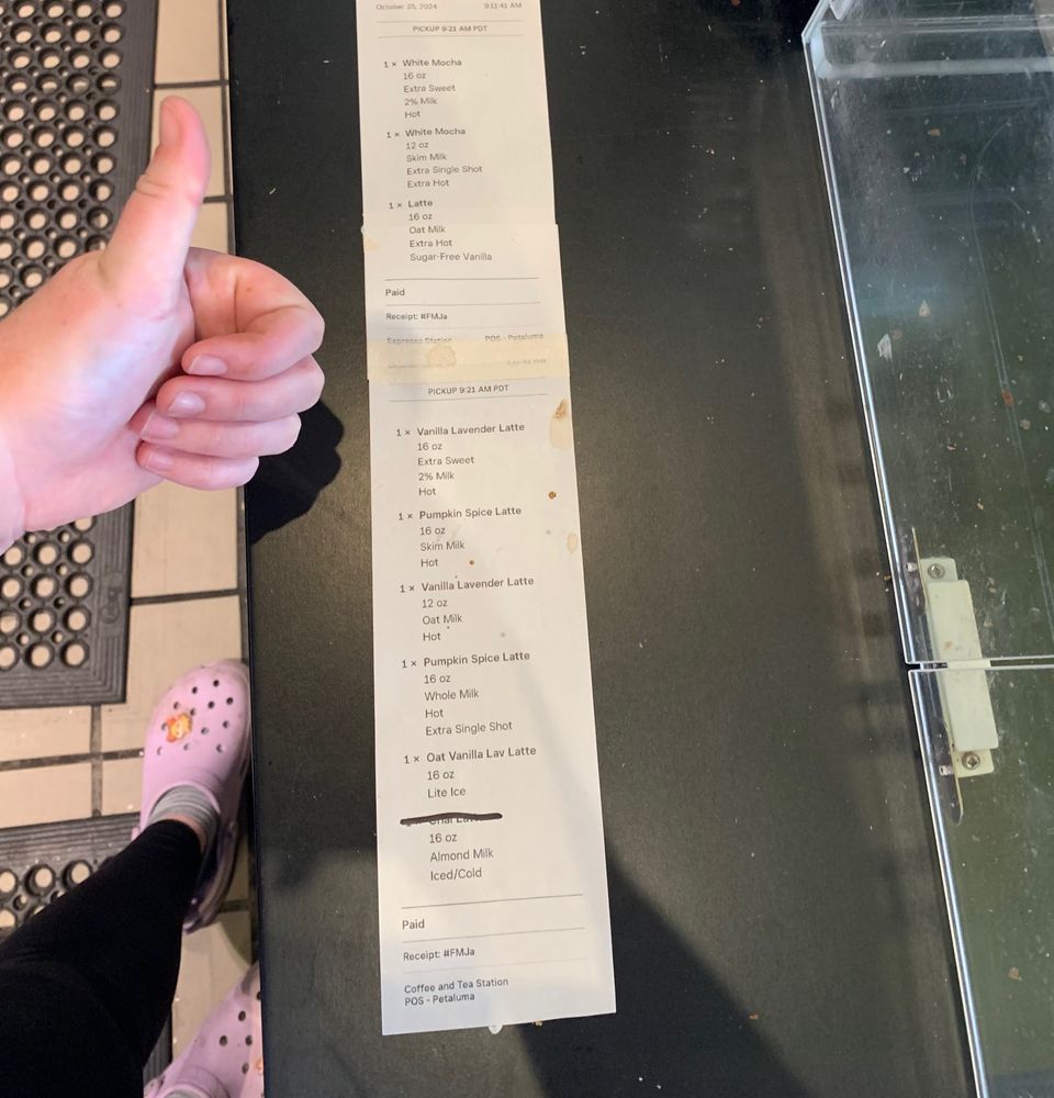 A receipt showing 9 drinks for one to-go order. A person giving a thumbs up is to the left of it