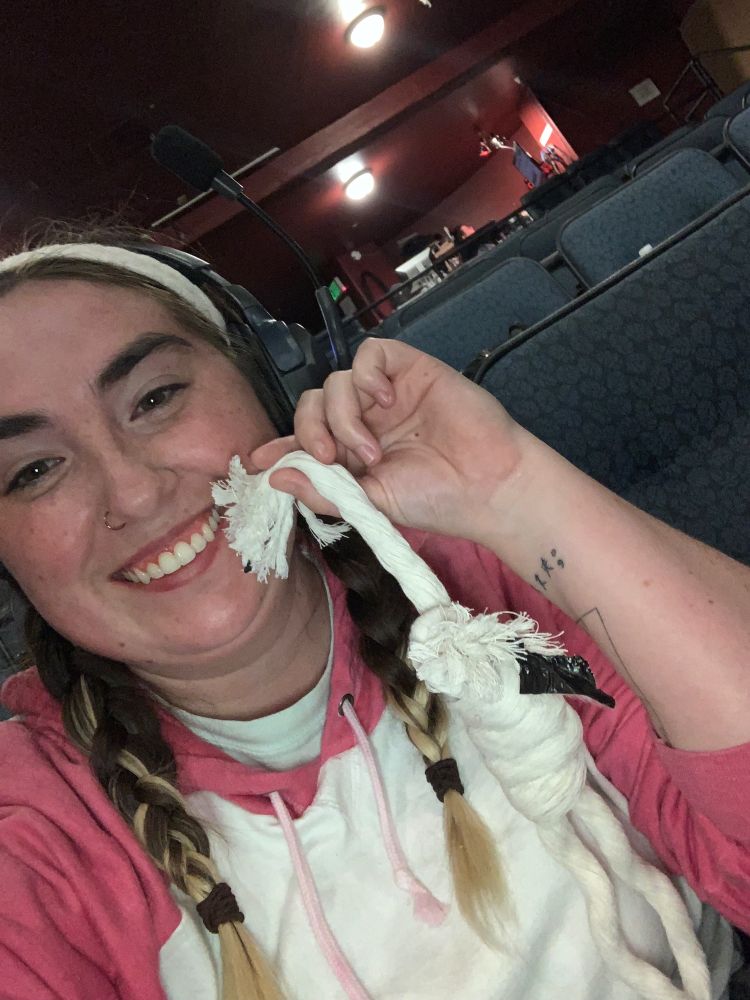 A girl holding up a small rope tied like a noose, her semi-colon tattoo on her wrist is shown