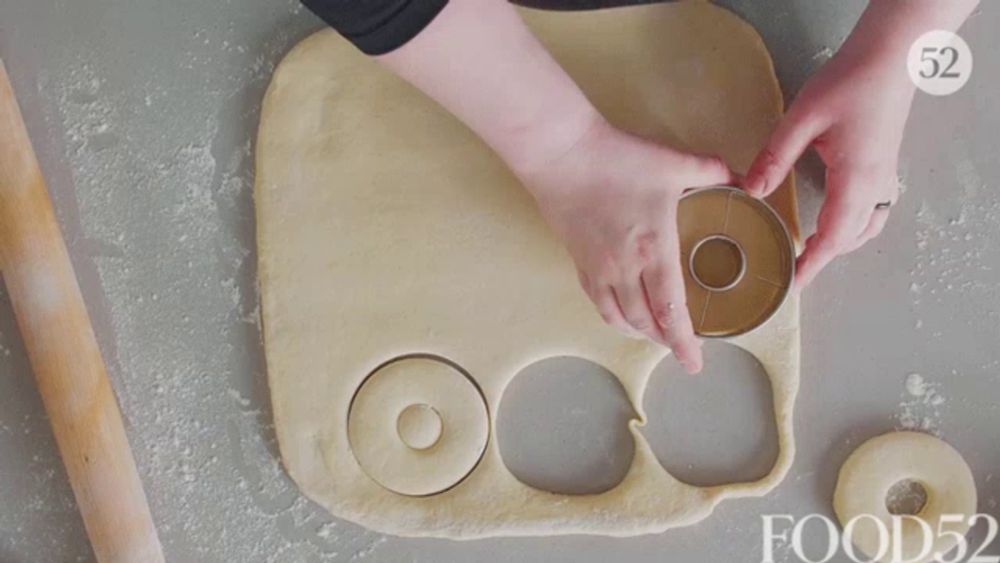 a person is cutting a donut out of a piece of dough that says food52 on it