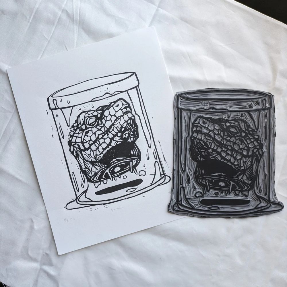 Linocut Print depicting the head of Kaiman from fantasy manga Dorohedoro in a jar. The print appears alongside the hand carved linoleum block.