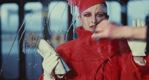 Woman in red behind a window, a hand washing said window in front. Iconic.