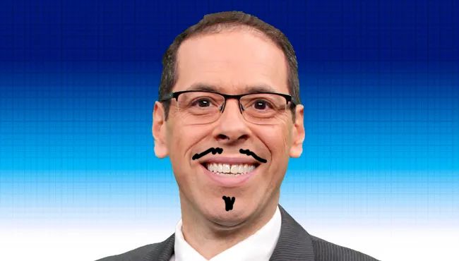 Massachusetts weatherman Brian Lapis, a smiling man wearing glasses and a dark suit jacket, stands in front of a blue gradient background. He has short dark hair and is looking directly at the camera with a friendly, if confused expression. A cartoonish black mustache and goatee have been drawn on his face.