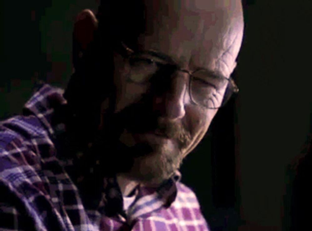 a bald man wearing glasses and a plaid shirt is talking on a phone