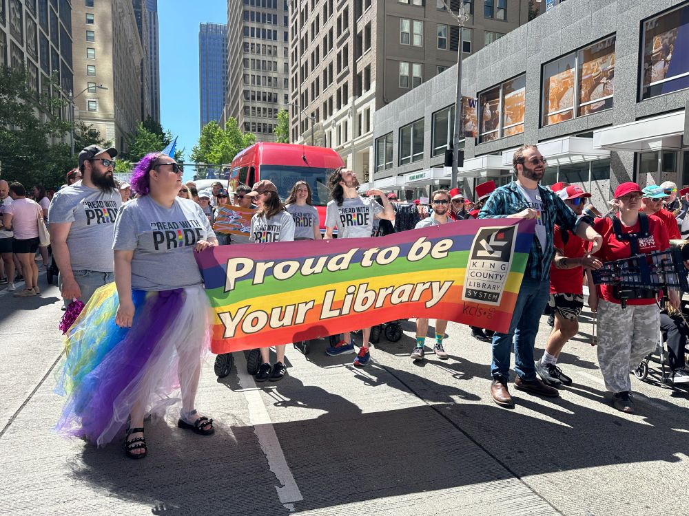 KCLS staff walking in the Seattle Pride Parade with a "Proud to be Your Library" banner.