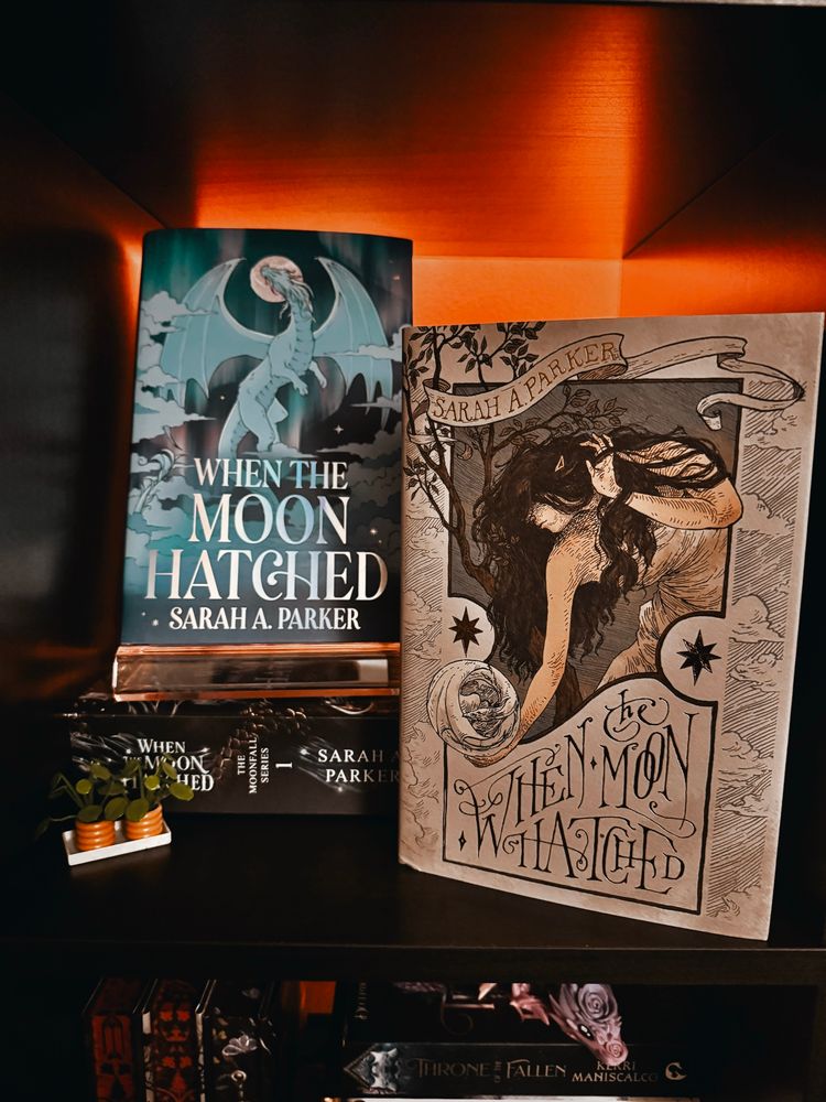 Photo of a bookshelf that features multiple editions of When The Moon Hatched by Sarah A Parker (fight me)