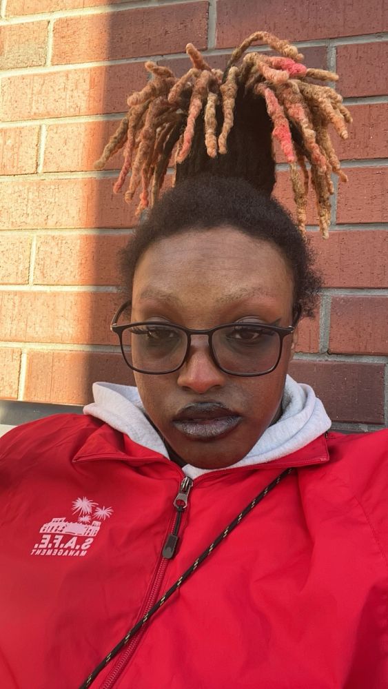 Dezzi wearing red jacket with a high loc ponytail