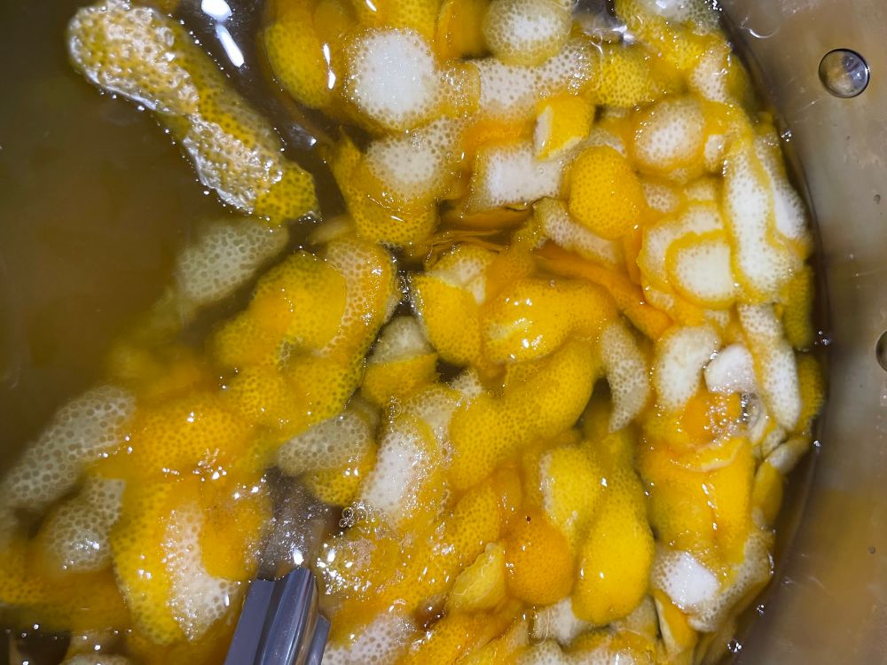 A big pot filled with strips of lemon rind, lemon juice, water and sugar. 