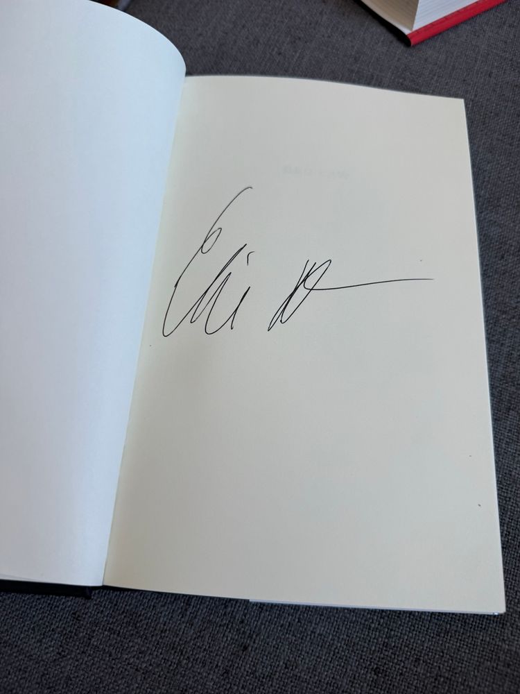 A scrawl, reminiscent of a name, written in ink on an otherwise blank page of a book. 