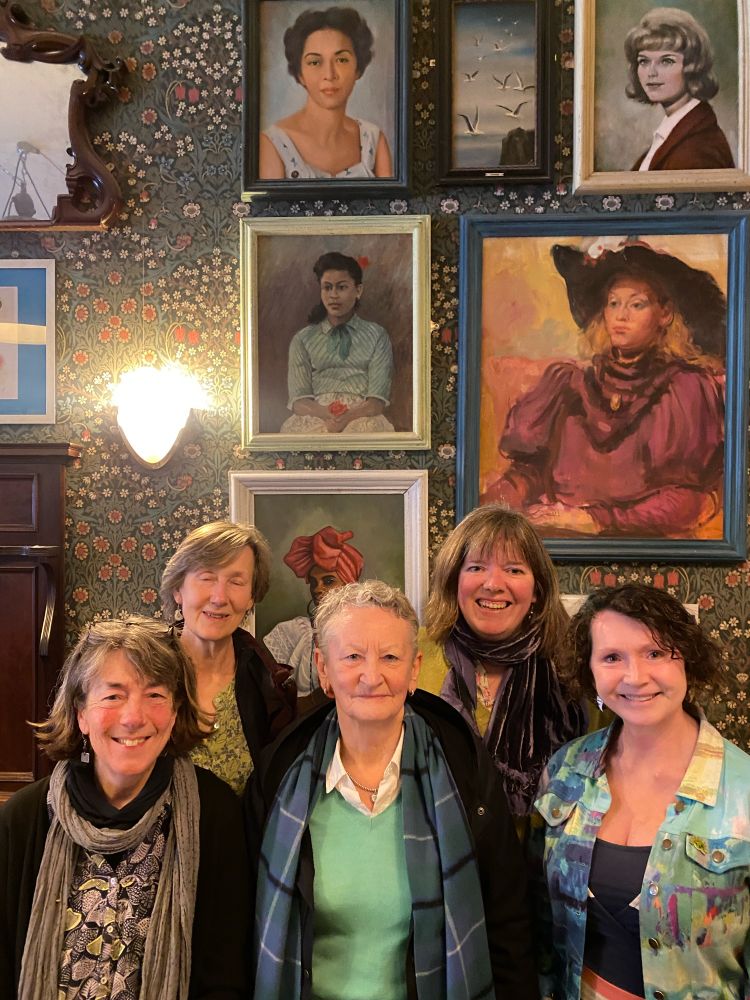 Green councillors and members with Green peer Jenny Jones (centre) in front of a range of pictures of women at Puerto Lounge Exeter quay. 