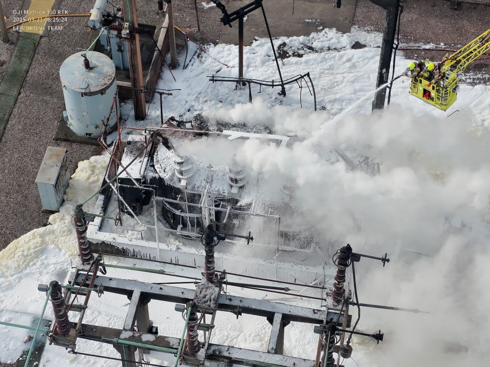 Firefighters pour foam over an electrical substation 