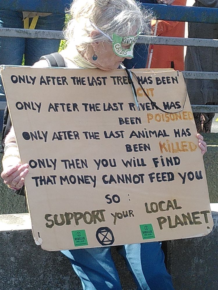 Mooi protestbord: "only after the last tree has been cut, the last river poisened, the last animal killed, then you will find that money cannot feed you, so support your local planet"