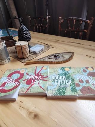 Interior of a northwoods cabin with four Northern Lakes Mystery books on a wooden table. 

