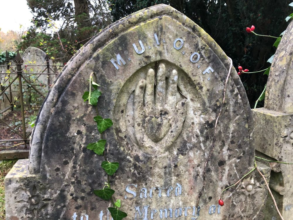 A gravestone with a hand with a heart in its palm