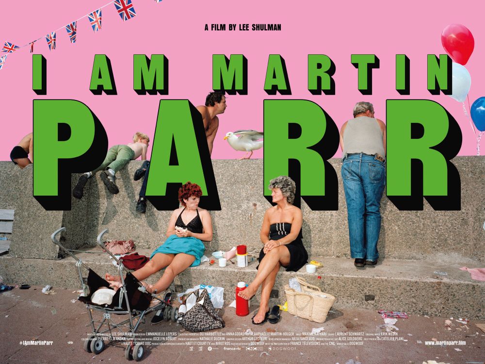 Poster for the documentary ‘I Am Martin Parr’ showing one of his photos of a family on a seaside pier, surrounded by picnic detritus and litter.