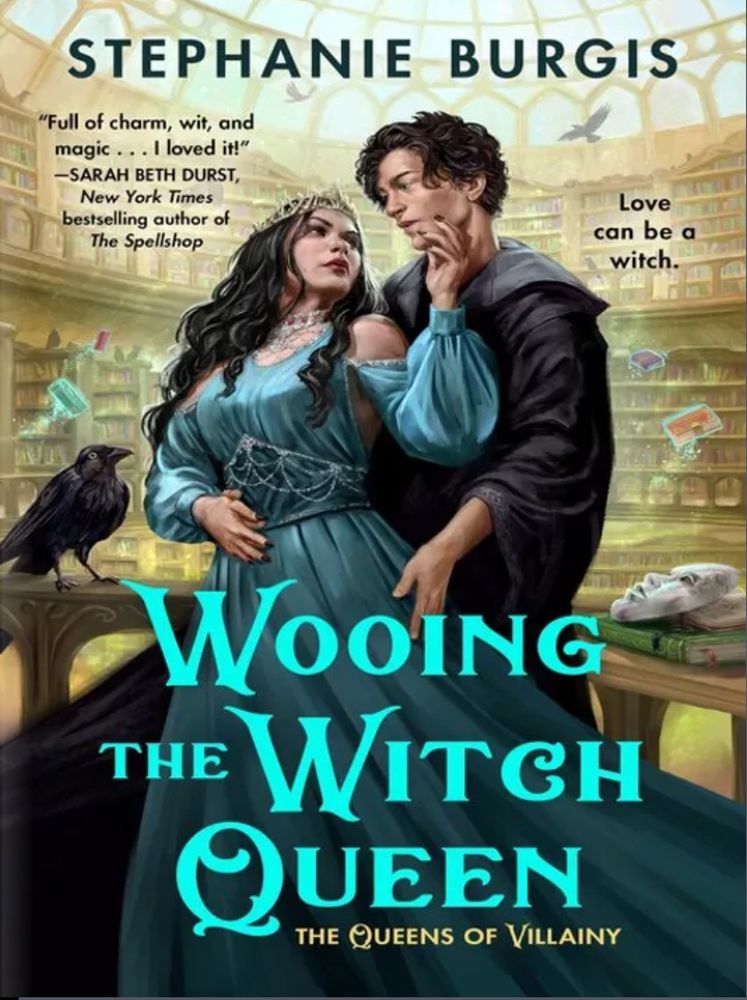 A beautiful dark haired witch queen with a crown of thorns in a teal dress looking over her shoulder at a handsome young man in a black robe. Her hand is on his cheek. They are standing in a library and a fat crow is looking at them from a nearby table. #romancelandia #bookteviews