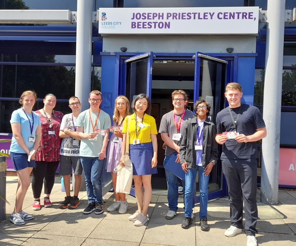 A group of students, staff and Healthwatch staff smiling while standing outside the Joseph Priestley Centre at Leeds City College in Beeston.