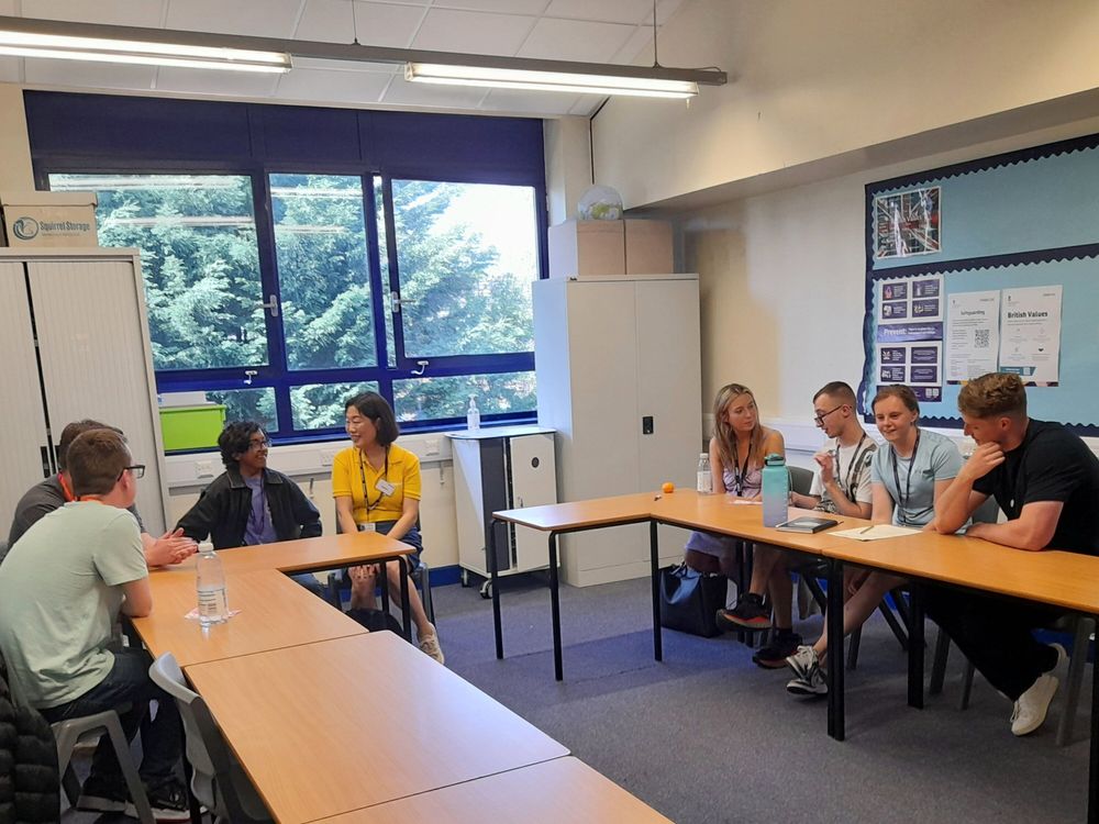 The same group of people in a classroom setting chatting and smiling.
