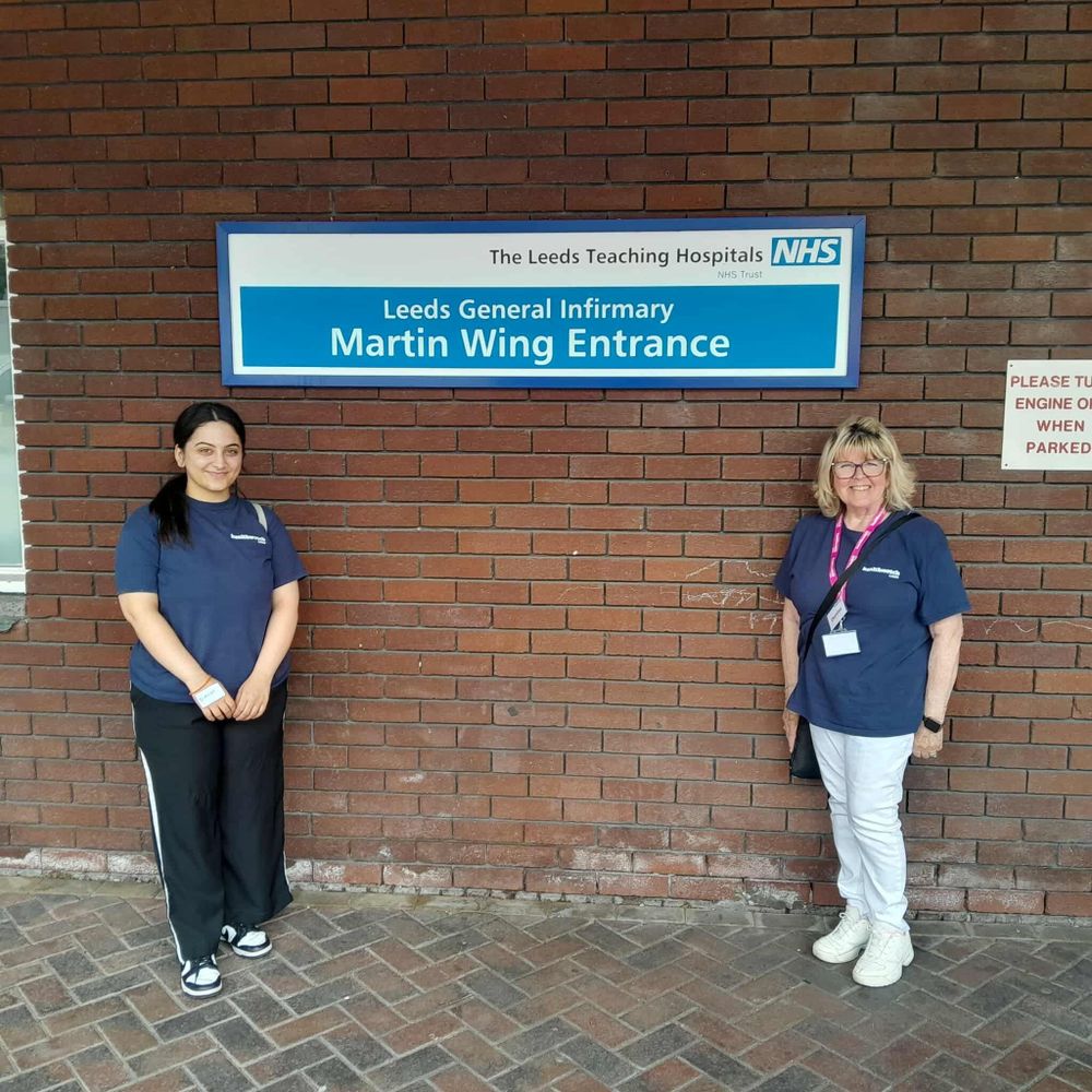 Healthwatch Leeds Volunteer stood at a sign for the Leeds General Infirmary, Martin Wing